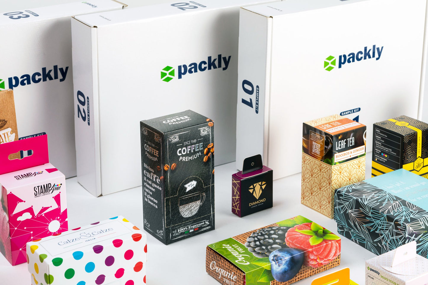 Focus on some boxes with various designs and, in the background, sample holder boxes with the Packly logo.