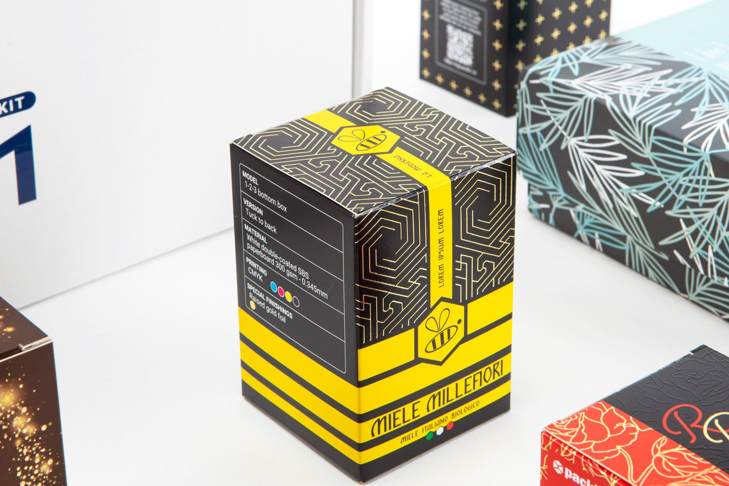 Overhead photo of several boxes, focusing mainly on a black and yellow one with the text ""Miele millefiori."