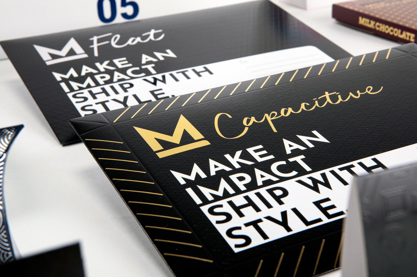 Focus on two capacitive cardboard envelopes, black in color, with white and yellow writing.
